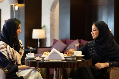 two women sitting at a table in a room at Holiday Inn Tabuk by IHG in Tabuk