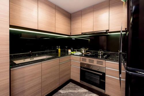a kitchen with wooden cabinets and stainless steel appliances at Qiss Residence by Bliston in Bangkok