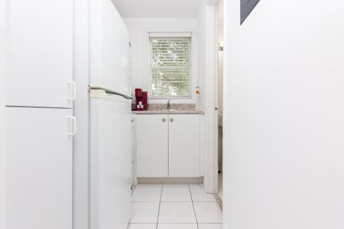 a white kitchen with a sink and a window at Studio Fort Lauderdale - 5 minutes walk to Las Olas Beach in Fort Lauderdale