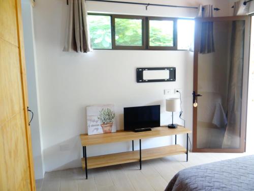 a bedroom with a desk with a television on it at Airport Green Studio in Santiago Este