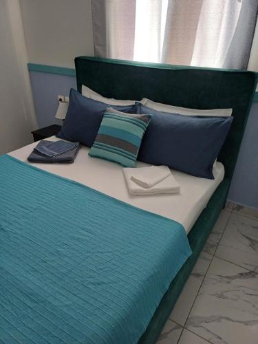 a bed with blue and green pillows on it at Hari Apartments Vathi, Agios Nikolaos Crete in Vathi