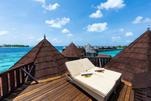 a deck with a chaise lounge on the water at Nika Island Resort & Spa, Maldives in Nika Island