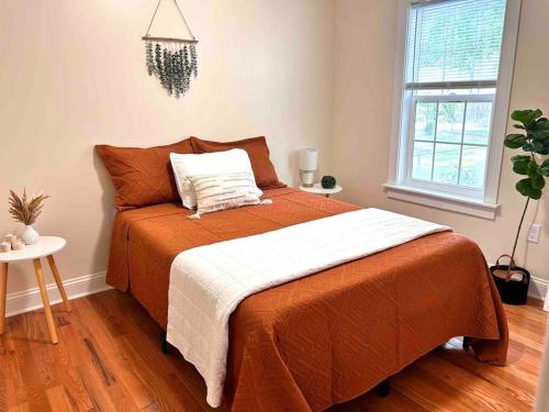 ein Schlafzimmer mit einem großen Bett mit einer orangefarbenen Decke in der Unterkunft Cozy Boho Home Close to Short North/OSU Campus/Downtown in Columbus