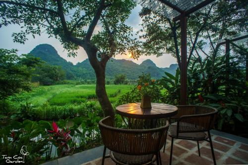a table and chairs on a patio with mountains in the background at Tam Coc Garden Resort in Ninh Binh
