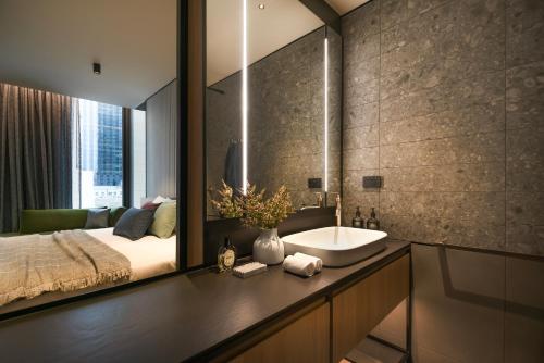 a bathroom with a sink and a bed and a mirror at The Howey in Melbourne