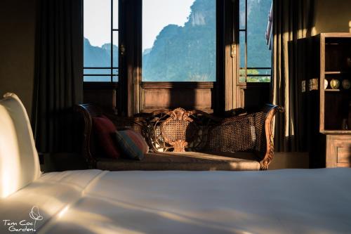 a hotel room with a bed and a couch and windows at Tam Coc Garden Resort in Ninh Binh
