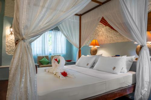 a bedroom with a white bed with a canopy at Nika Island Resort & Spa, Maldives in Nika Island