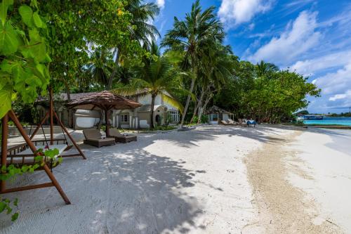 - une plage avec une maison et des arbres dans l'établissement Nika Island Resort & Spa, Maldives, à Nika Island