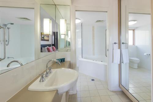 ein weißes Bad mit einem Waschbecken und einer Dusche in der Unterkunft Club Wyndham Coffs Harbour Terraces in Coffs Harbour