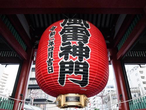 una linterna roja con escritura colgando de un edificio en Vessel Inn Asakusa Tsukuba Express en Tokio