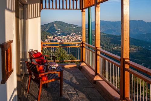 a balcony with two chairs and a view of the mountains at Taj Theog Resort & Spa Shimla in Shimla