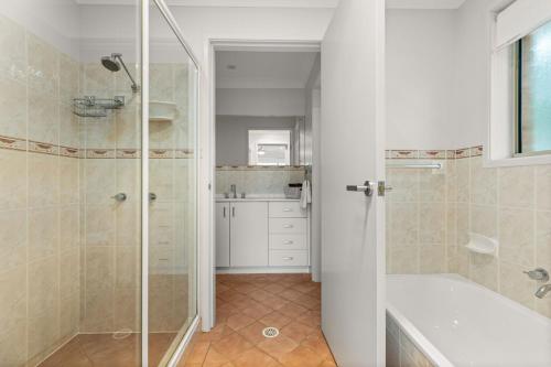 a bathroom with a shower and a tub and a sink at Berry Haven by Experience Jervis Bay in Vincentia