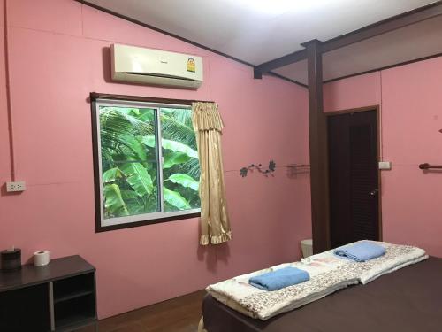 um quarto com uma parede rosa e uma janela em บ้านปุณยาพร โฮมสเตย์ em Amphawa