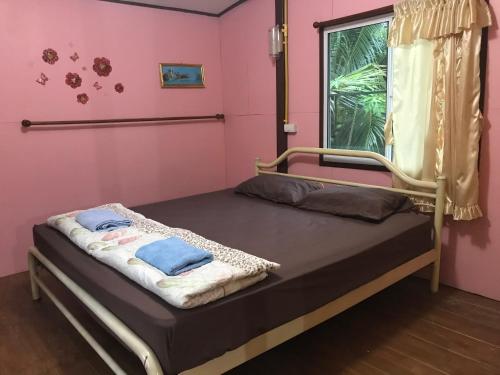 uma cama num quarto com uma parede rosa em บ้านปุณยาพร โฮมสเตย์ em Amphawa