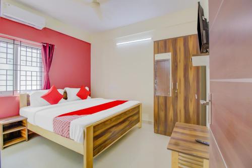 Un dormitorio con una cama y una pared roja. en Hotel O Nelli Suites, en Bangalore