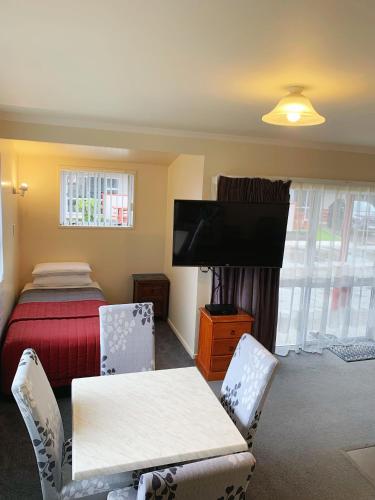 a bedroom with a bed and a table and chairs at Amber Court Motel in Te Anau