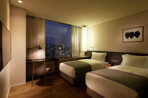 a hotel room with two beds and a desk and a window at Shilla Stay Mapo Hongdae in Seoul