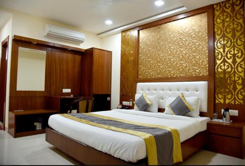 a bedroom with a large bed and a mirror at Hotel Simran Pride, Raipur in Raipur