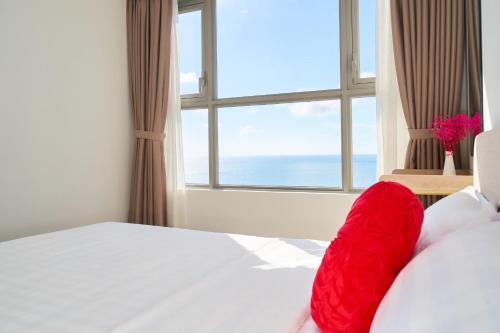 a bedroom with a red pillow on a bed with a window at THE SONG- CĂN HỘ DU LỊCH 5SAO- FREE hồ bơi- Gần biển - LUXYRY PALM HOME in Vung Tau