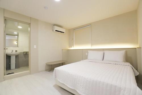 a bedroom with a large white bed and a sink at Chuncheon Pine Tree Hotel in Chuncheon