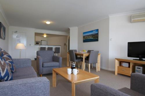 a living room with chairs and a tv and a table at Club Wyndham Port Macquarie in Port Macquarie