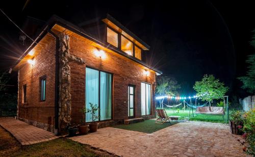a brick house with a patio at night at WoodStar/ტყის ვარსკვლავი in Ambrolauri