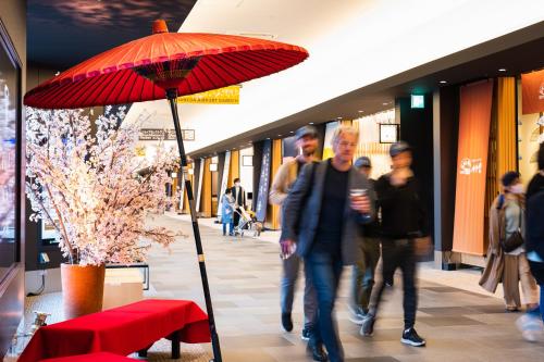 a man standing next to a red umbrella in a shopping mall at Villa Fontaine Grand Haneda Airport in Tokyo