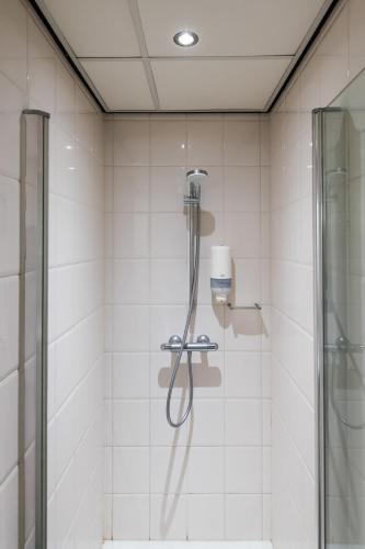 a shower in a bathroom with white tiles at Japie rooms - in the heart of Antwerp in Antwerp