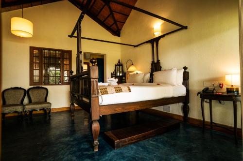 a bedroom with a large bed and two chairs at Cranganor History Café & Riverside Château in Parūr