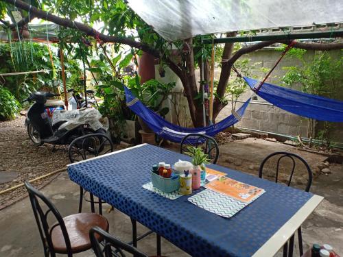 a blue table with chairs and a hammock at Baanchaokoh Homestay in Kanchanaburi