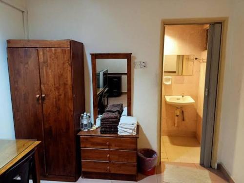 a bathroom with a wooden cabinet and a sink at OYO 90842 Hotel Prai Jaya in Perai