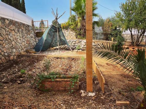 un jardín con una tienda y una pared de piedra en יחידת אירוח גלילית en Hatzor haglilit
