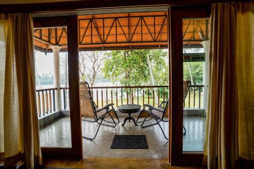 a porch with chairs and a table on a balcony at Cranganor History Café & Riverside Château in Parūr