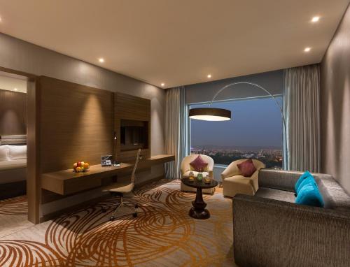 ジャイプールにあるホリデイ イン ジャイプール シティ センターのソファ、ベッド、窓が備わるホテルルームです。