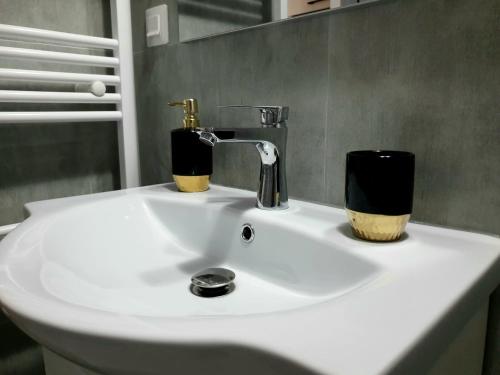 a white bathroom sink with two cups on it at Enjoy BDF in Vatra Dornei