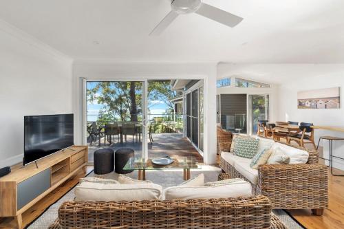 a living room with a couch and a tv at Treehaven Hyams Beach in Hyams Beach