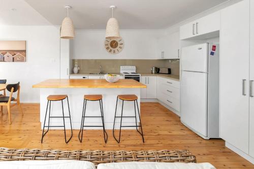 a kitchen with a table and two bar stools at Treehaven Hyams Beach in Hyams Beach