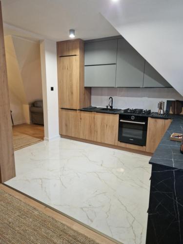 a kitchen with marble flooring and wooden cabinets at Nowodworski in Nowy Dwór Gdański