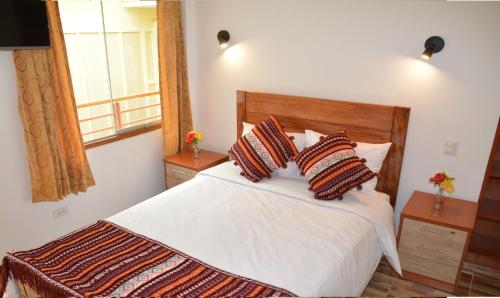 a bedroom with a white bed with pillows and a window at Hotel Inka Pisac in Pisac