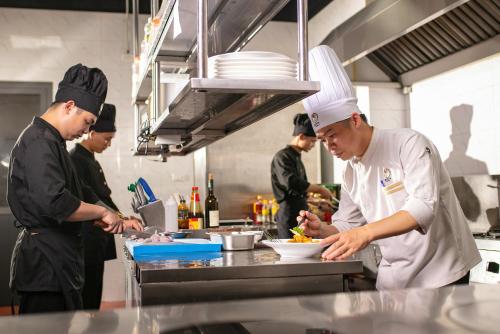 a group of chefs preparing food in a kitchen at Nesta - The Grand Hao Nam in Hanoi