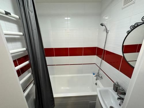 a bathroom with a white tub and red and white stripes at Cozy Two Room Apartment near city centre in Alytus