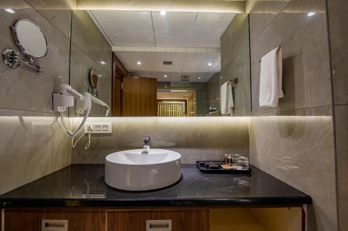 uma casa de banho com um lavatório e um espelho grande em The Imperial Inn em Siliguri