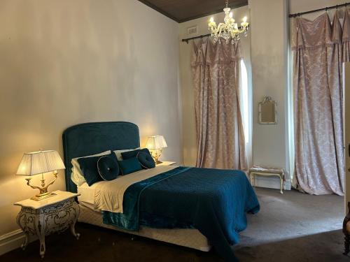 a bedroom with a blue bed and a chandelier at Convent at Koroit in Koroit