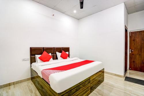 een slaapkamer met een groot wit bed met rode kussens bij Flagship Hotel Aashirvad in Faridabad