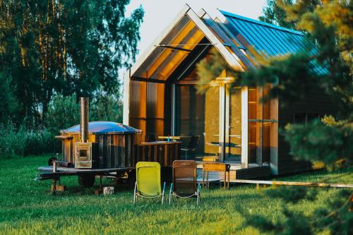 a small house with a table and chairs in the grass at Duseli Holiday House Tutti in Klīvji