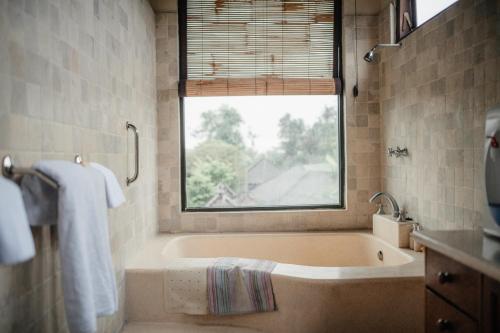 a bathroom with a bath tub and a window at Mandala Desa in Sukawati