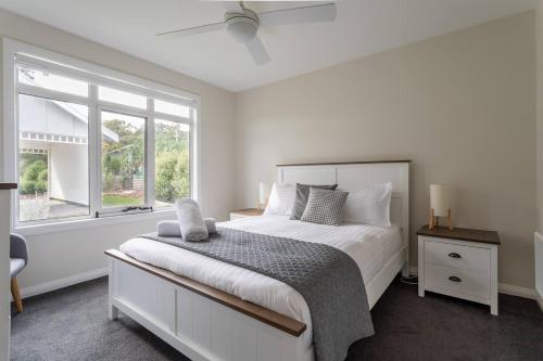 a white bedroom with a large bed and a window at Derwent River Cottage - Tranquil Waterfront Living in Goodwood