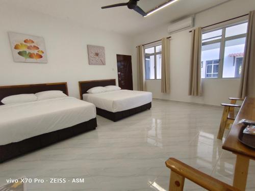 a hotel room with two beds and a table at ASM Roomstay-4-2 Queen Beds in Kuala Terengganu