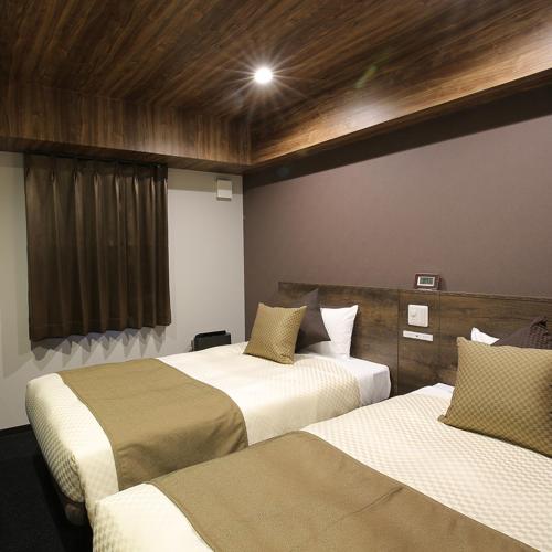 a hotel room with two beds and a window at The Celecton Matsumoto in Matsumoto