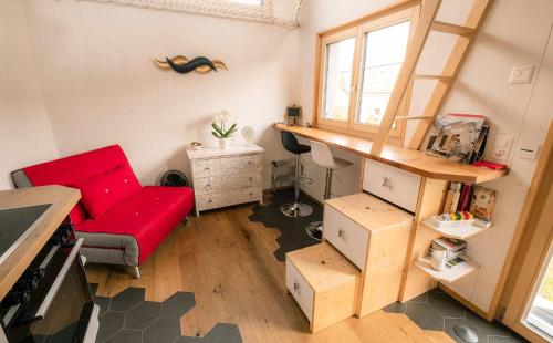 ein Wohnzimmer mit einem roten Sofa und einem Tisch in der Unterkunft Tiny de l'Aigle in Villeret